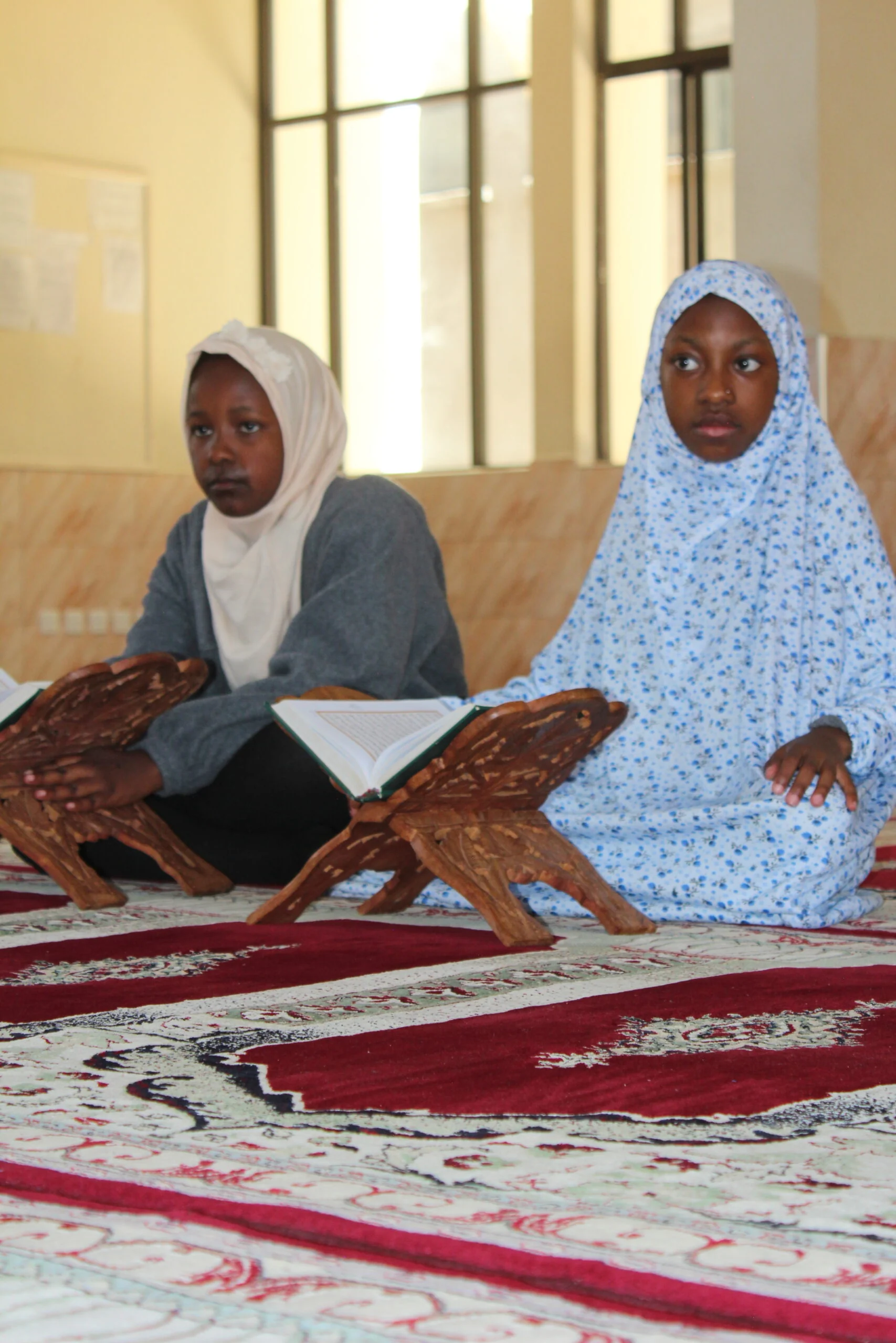 Pupils in Hijab Reading Quran on Wooden Rehal