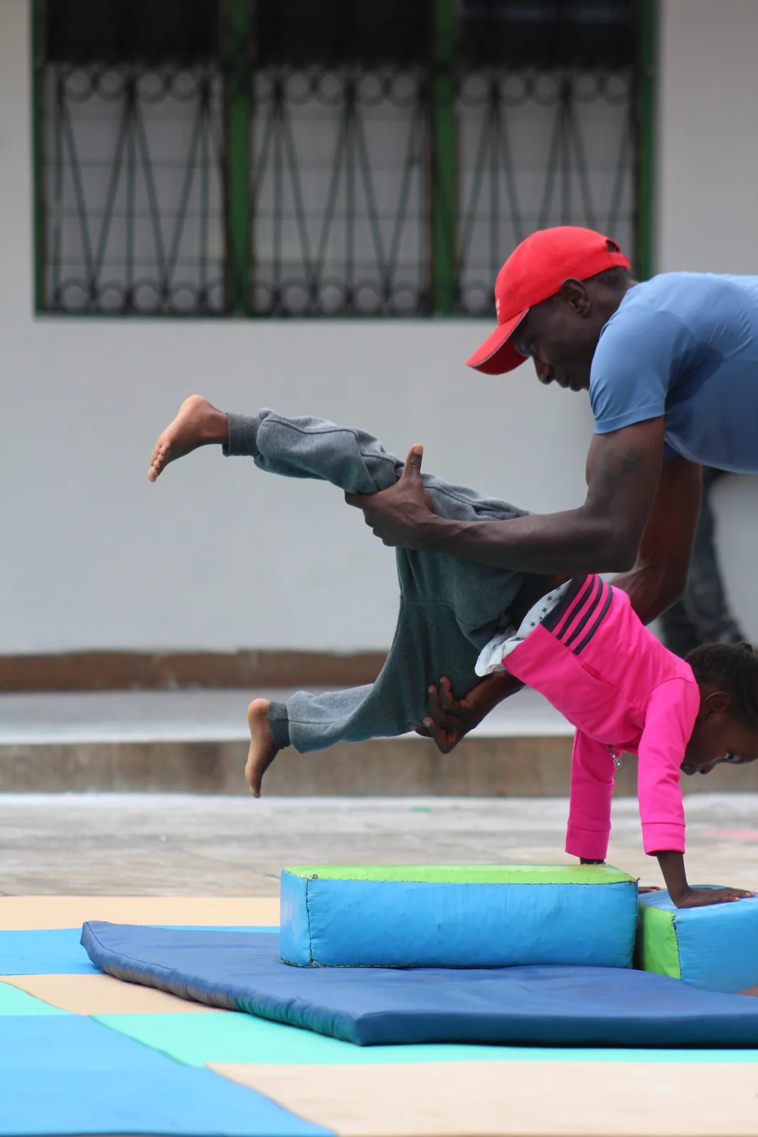 Gymnastics Coach Supporting Inverted Handstand on Safety Mats